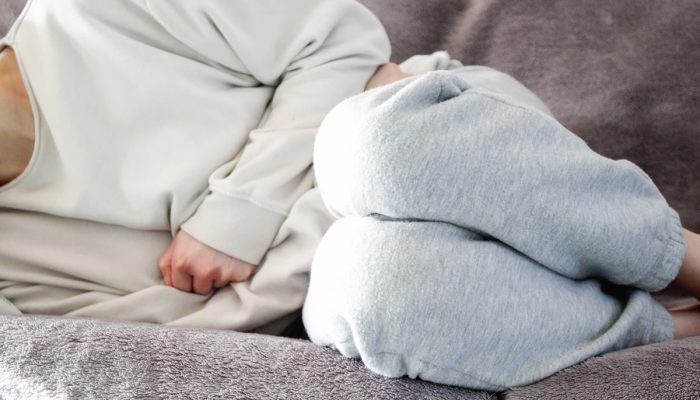 1 de 1 Mulher com pijama branco com cólica deitada em sofá - Ginecologistas explicam os princip...