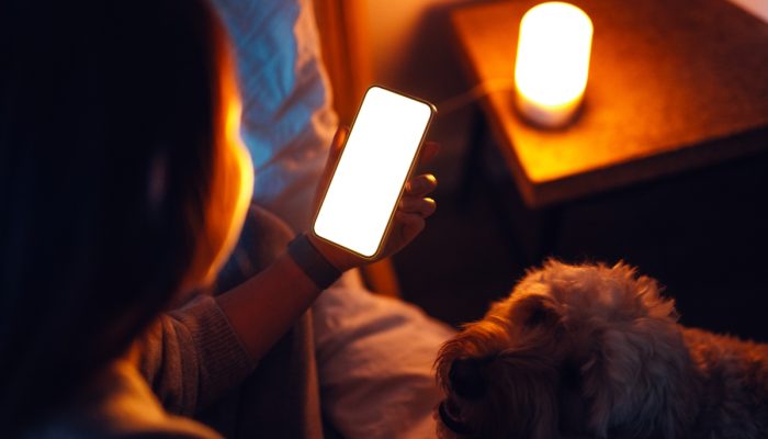 1 de 1 mulher mexendo no celular ao lado de cachorro - Foto: Oscar Wong/Getty Images