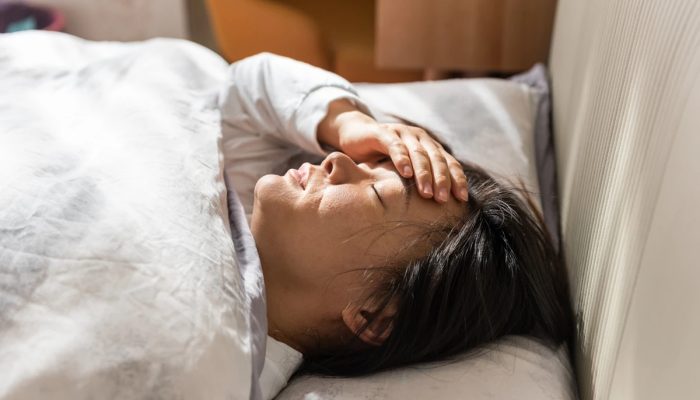 1 de 1 Jovem mulher asiática com a mão no rosto deitada em cama - Metrópoles - Foto: Getty Images