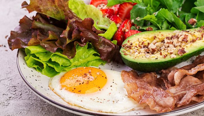 1 de 1 Prato com alimentos da dieta cetogênica. Ovo frito, bacon, abacate, rúcula e morangos. C...