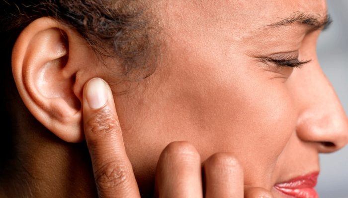 1 de 1 Fotografia mostra mulher de perfil. Ela está apertando a orelha com um dedo e de olhos fe...