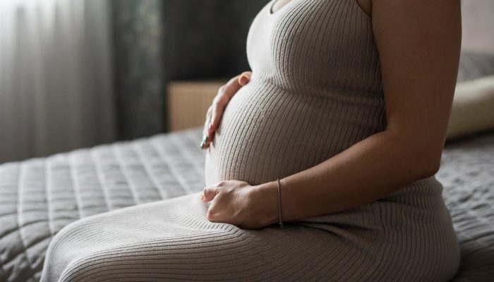 1 de 1 Foto colorida de mulher grávida sentada na cama, com close na barriga - Metrópoles. - Fo...