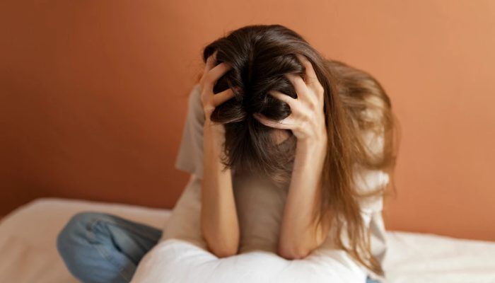 1 de 1 Foto mostra uma mulher sentada ela apoia as mãos na cabeça como se estivesse com dor de ...