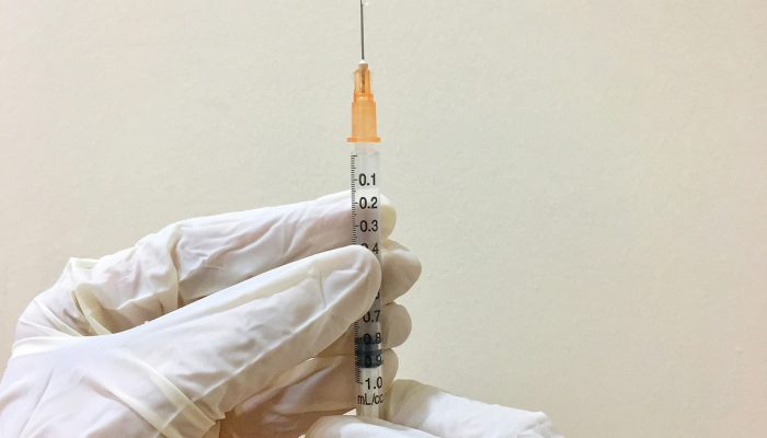 1 de 1 Foto colorida de pessoa com luvas de borracha segurando uma seringa de ponta laranja e agu...